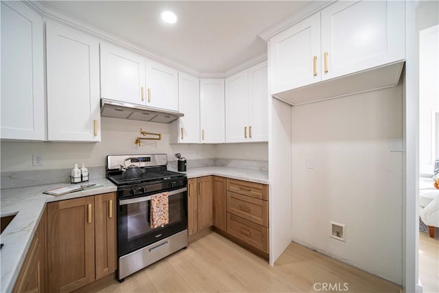 kitchen with light stone counters, white cabinets, light hardwood / wood-style flooring, and stainless steel gas stove