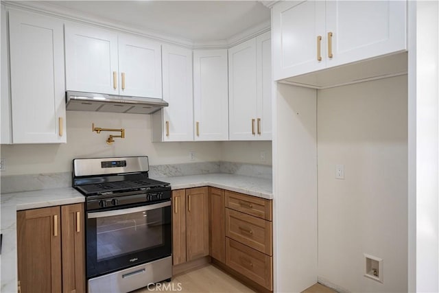 kitchen featuring gas range, light stone countertops, and white cabinets