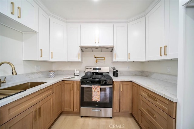 kitchen featuring sink, light stone counters, light hardwood / wood-style floors, white cabinets, and stainless steel range with gas cooktop