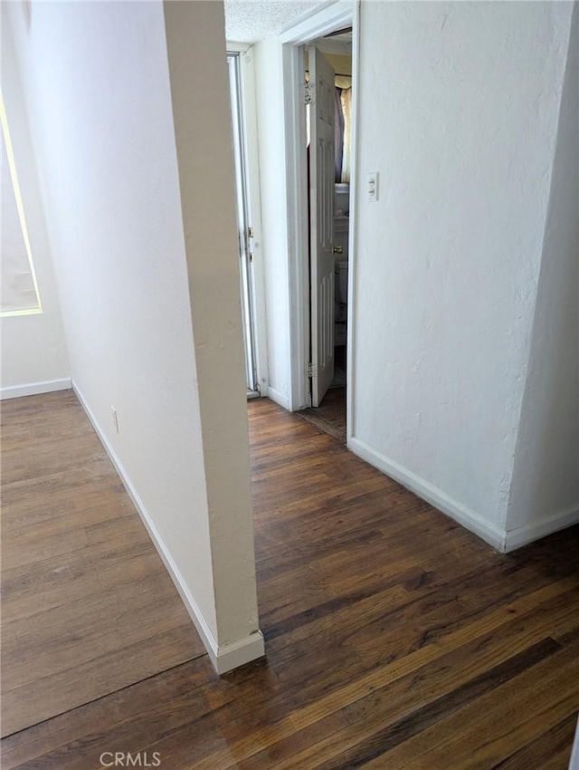 hallway featuring dark hardwood / wood-style floors and a textured ceiling