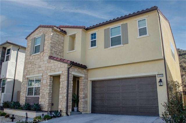 mediterranean / spanish house featuring a garage, driveway, a tiled roof, and stucco siding