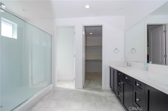 bathroom with a stall shower, a walk in closet, vanity, and recessed lighting