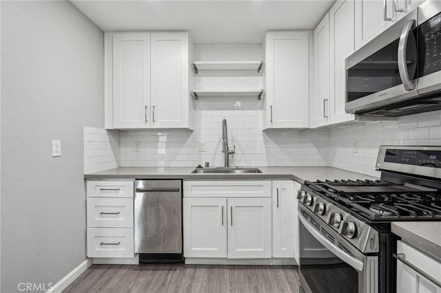 kitchen with sink, stainless steel appliances, white cabinets, and light wood-type flooring