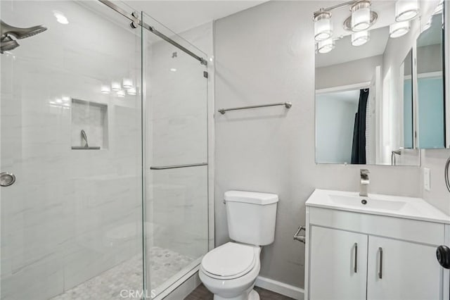 bathroom featuring a shower with door, vanity, and toilet