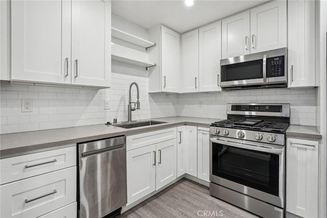 kitchen featuring sink, light hardwood / wood-style flooring, white cabinets, stainless steel appliances, and backsplash