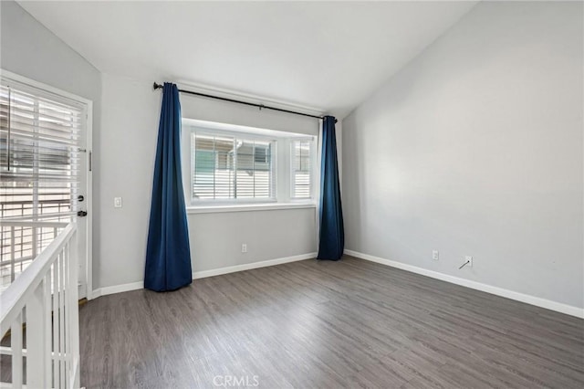 spare room featuring dark wood-type flooring and vaulted ceiling