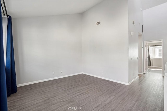 empty room with vaulted ceiling and dark hardwood / wood-style flooring