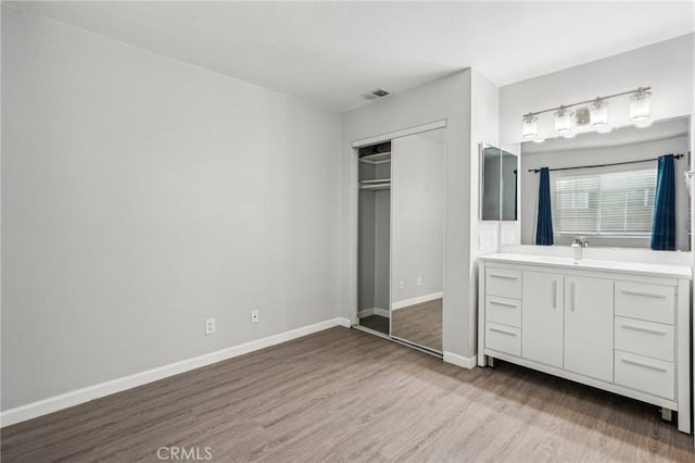 unfurnished bedroom featuring sink, light wood-type flooring, and a closet