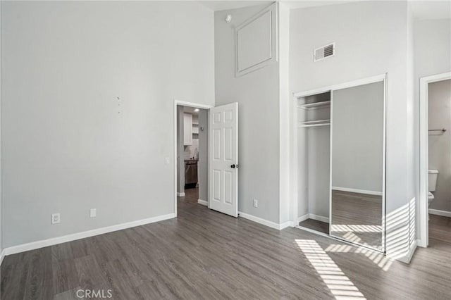 unfurnished bedroom with dark hardwood / wood-style flooring, a closet, and a high ceiling