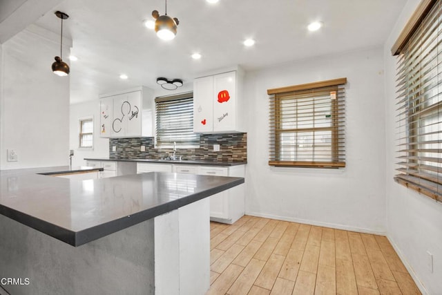 kitchen featuring pendant lighting, white cabinets, backsplash, and kitchen peninsula