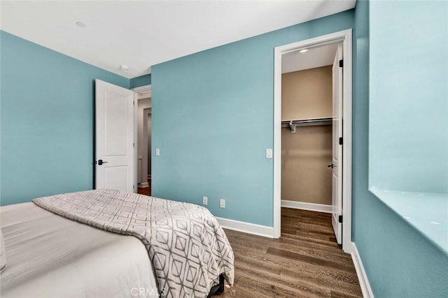 bedroom featuring a walk in closet, dark wood-type flooring, and a closet