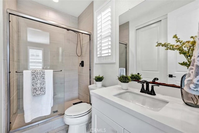 bathroom with toilet, vanity, and a shower with shower door