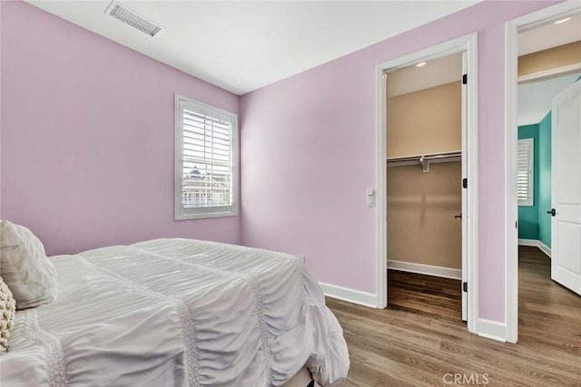 bedroom with wood-type flooring and a spacious closet