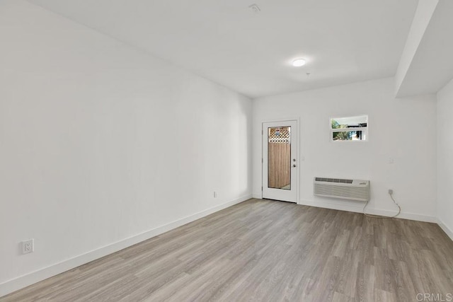 unfurnished room with light hardwood / wood-style flooring and an AC wall unit