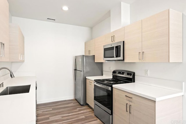 kitchen with wood-type flooring, appliances with stainless steel finishes, sink, and light brown cabinets