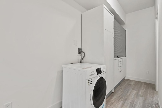 clothes washing area featuring washer / clothes dryer and light hardwood / wood-style floors