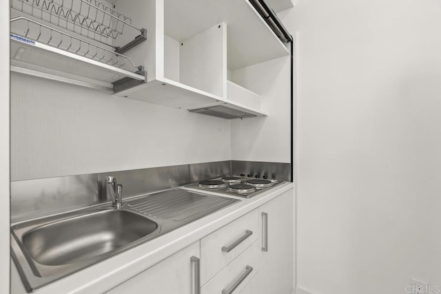 kitchen featuring ventilation hood, white cabinetry, sink, and stainless steel gas stovetop