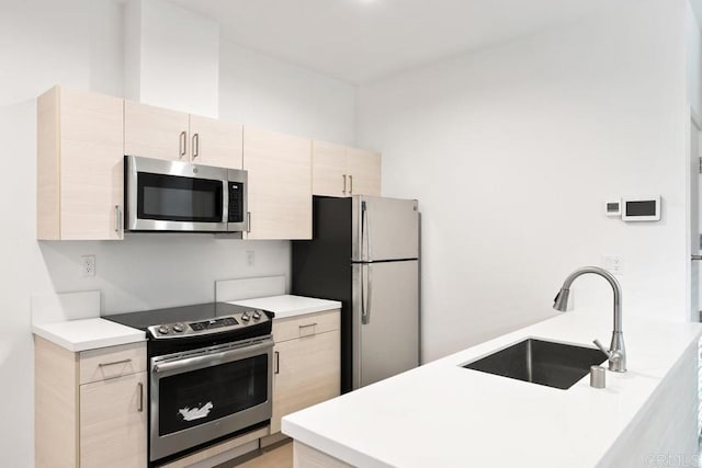 kitchen featuring appliances with stainless steel finishes, sink, and light brown cabinets
