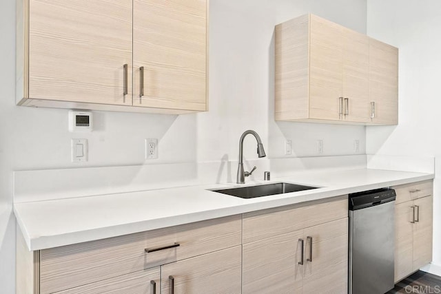 kitchen with stainless steel dishwasher, sink, and light brown cabinets