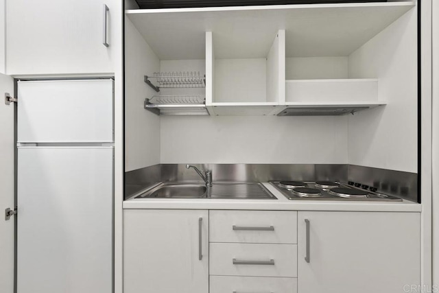 kitchen featuring white cabinetry, sink, stainless steel gas stovetop, and white refrigerator