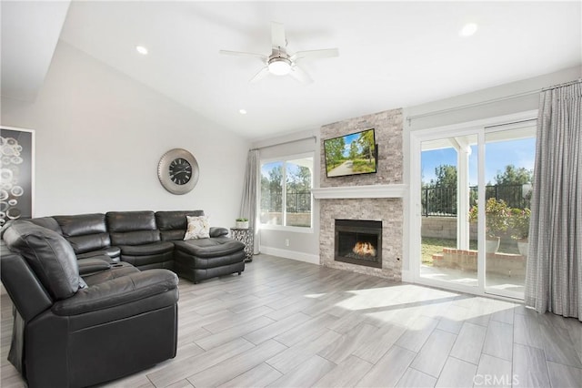 living room featuring a stone fireplace, vaulted ceiling, and ceiling fan