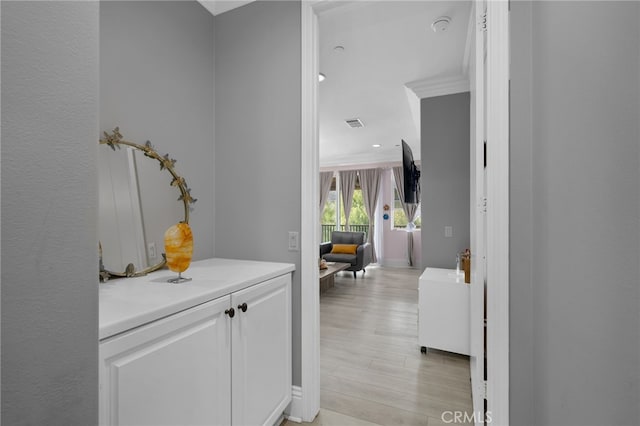 hallway with ornamental molding and light hardwood / wood-style floors