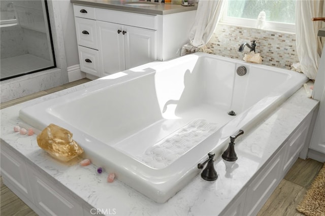 interior space with vanity, a bath, and hardwood / wood-style flooring