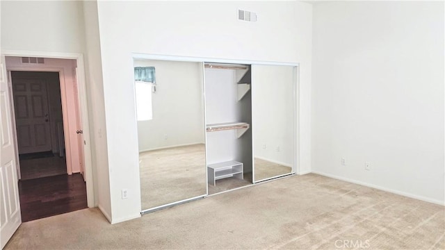 unfurnished bedroom with carpet, a closet, and visible vents