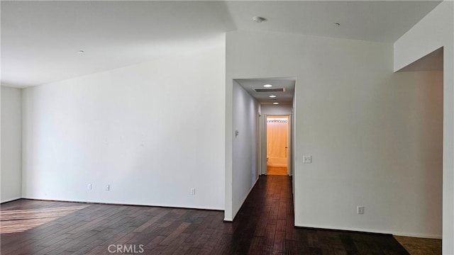 spare room with dark wood-style floors, lofted ceiling, and visible vents