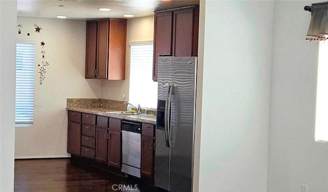 kitchen featuring baseboards, dark wood-style floors, light stone counters, stainless steel appliances, and a sink