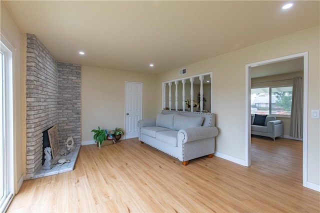 unfurnished living room featuring light wood-type flooring and a brick fireplace