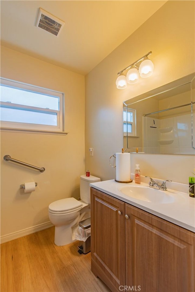 bathroom featuring hardwood / wood-style flooring, vanity, toilet, and a shower