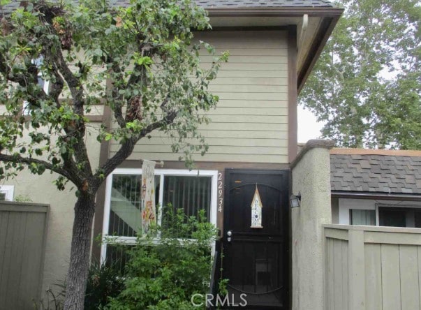 exterior space featuring a shingled roof and fence