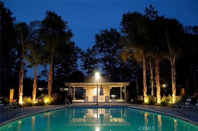 pool at twilight with an outdoor pool, a patio, and a pergola