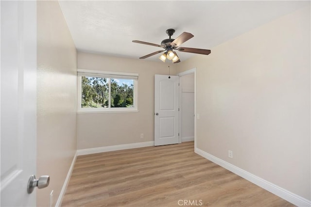 spare room with a ceiling fan, light wood-type flooring, and baseboards