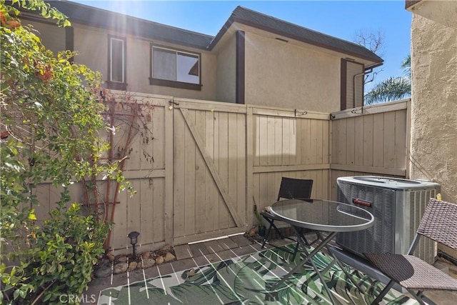 view of patio featuring central AC unit, outdoor dining area, and fence