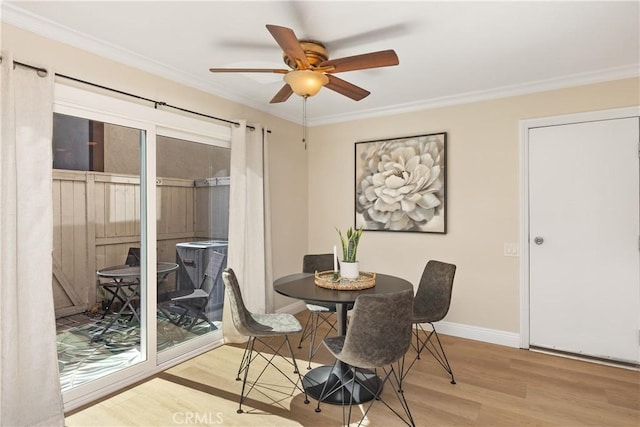 dining space featuring ceiling fan, crown molding, baseboards, and wood finished floors