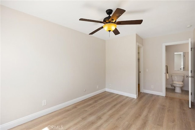 unfurnished bedroom with baseboards, ensuite bathroom, a ceiling fan, and light wood-style floors