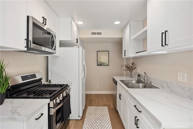 kitchen with light wood-style flooring, a sink, visible vents, appliances with stainless steel finishes, and open shelves