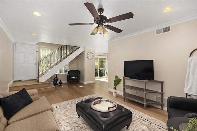 living room with stairway, visible vents, crown molding, and wood finished floors