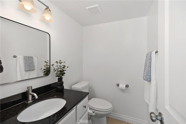 half bathroom with tile patterned flooring, toilet, vanity, visible vents, and baseboards