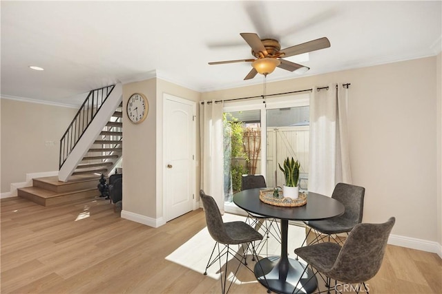 dining space with ornamental molding, stairway, light wood-type flooring, and baseboards