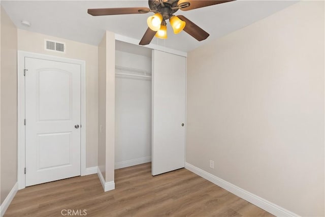 unfurnished bedroom with light wood-style flooring, a closet, visible vents, and baseboards