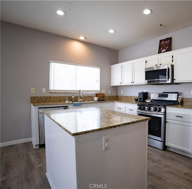 kitchen with a center island, appliances with stainless steel finishes, white cabinetry, and light stone countertops