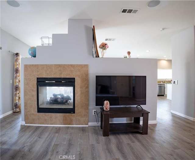 living room featuring a tile fireplace and hardwood / wood-style flooring