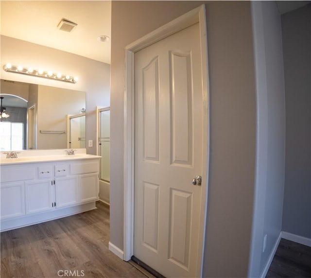 bathroom featuring wood-type flooring, combined bath / shower with glass door, and vanity