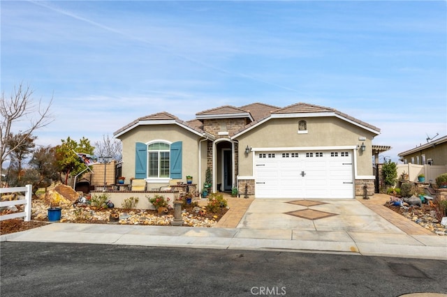 view of front of property with a garage, fence, stone siding, concrete driveway, and stucco siding