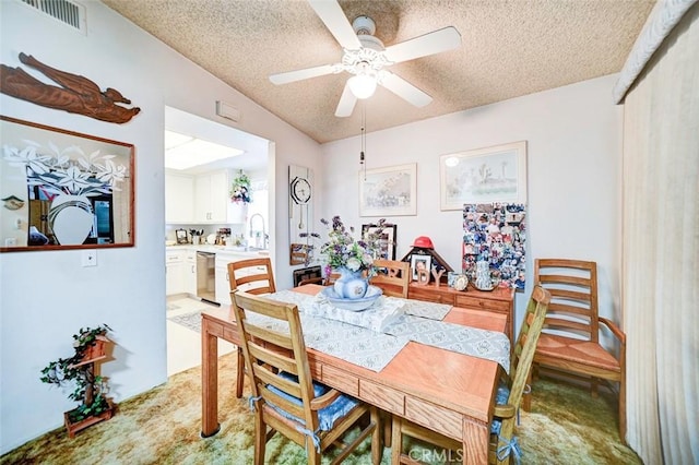 dining room with light carpet, ceiling fan, sink, and a textured ceiling