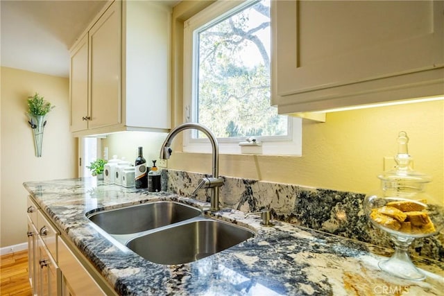 kitchen featuring sink, dark stone countertops, and light hardwood / wood-style flooring