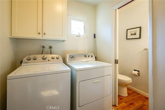 laundry area with separate washer and dryer, wood-type flooring, and cabinets